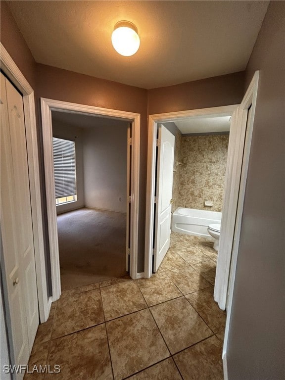 hall with a textured ceiling and light tile patterned floors