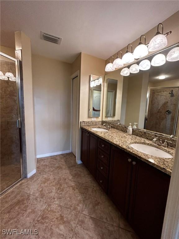 bathroom featuring vanity, a shower with shower door, and tile patterned flooring