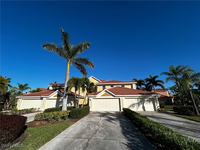 view of front facade with stucco siding, an attached garage, driveway, and a tiled roof