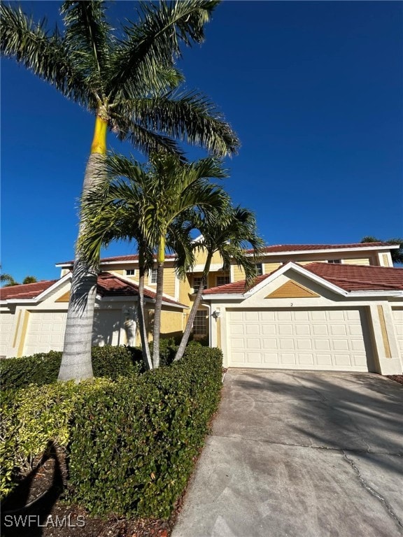 view of front of home with concrete driveway, a tiled roof, and stucco siding