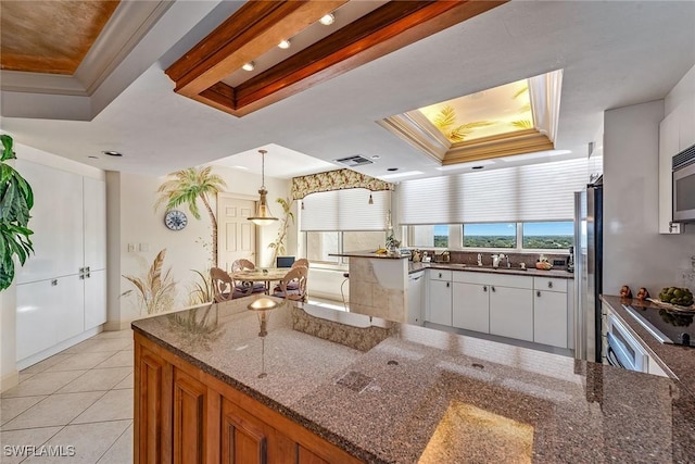 kitchen featuring a raised ceiling, dark stone countertops, crown molding, and white cabinets