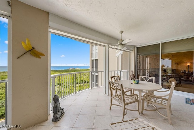 sunroom featuring a water view and ceiling fan