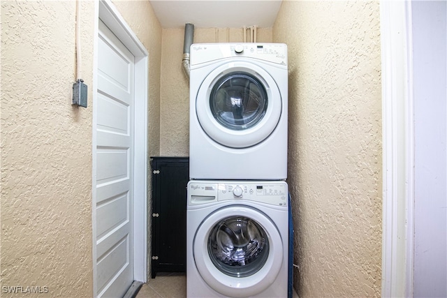 clothes washing area featuring stacked washer / drying machine and tile patterned floors