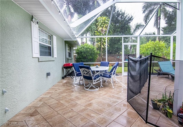 view of patio featuring a lanai, fence, and outdoor dining area