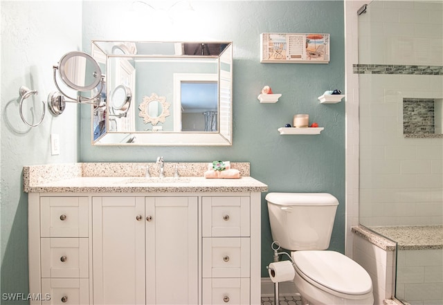 bathroom featuring tiled shower, toilet, and vanity