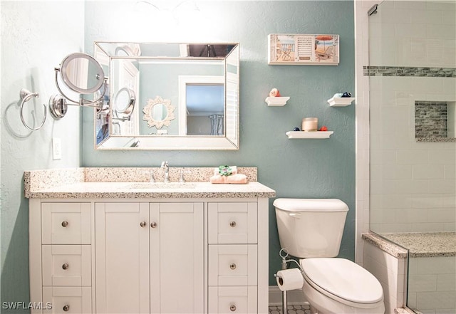 full bathroom featuring toilet, a textured wall, tiled shower, and vanity