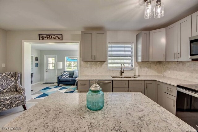 kitchen featuring sink, appliances with stainless steel finishes, light stone countertops, tasteful backsplash, and gray cabinetry