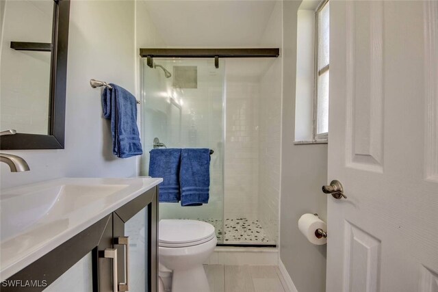 bathroom with toilet, an enclosed shower, and vanity