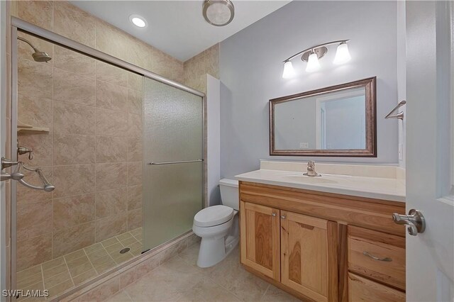 bathroom with a shower with door, toilet, tile patterned floors, and vanity