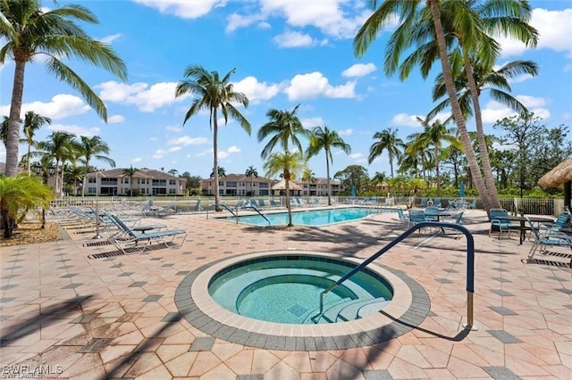 community pool featuring a community hot tub, a patio, and fence