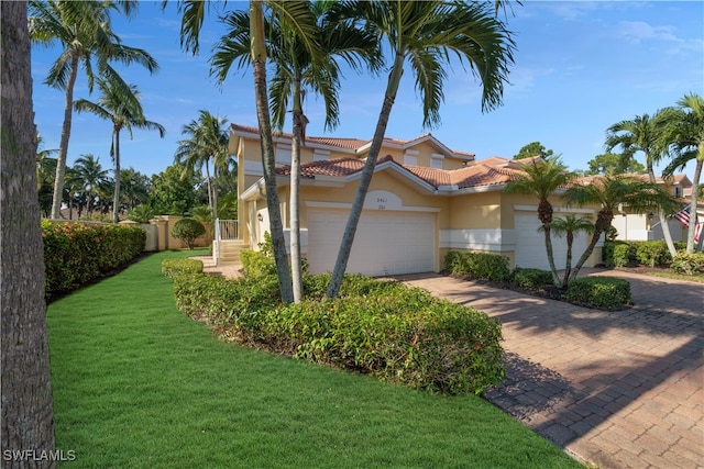 mediterranean / spanish home featuring a front yard and a garage