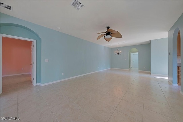 spare room with light tile patterned floors, visible vents, arched walkways, and ceiling fan with notable chandelier