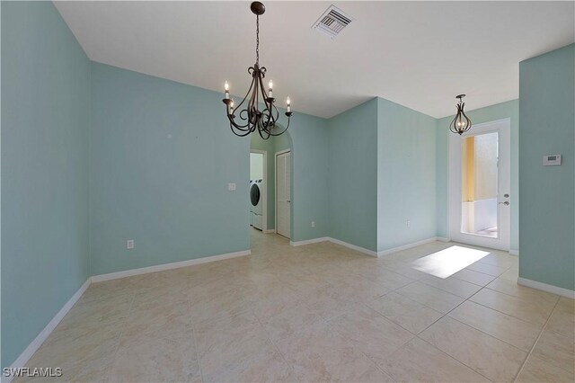 tiled spare room with a notable chandelier and washer / clothes dryer