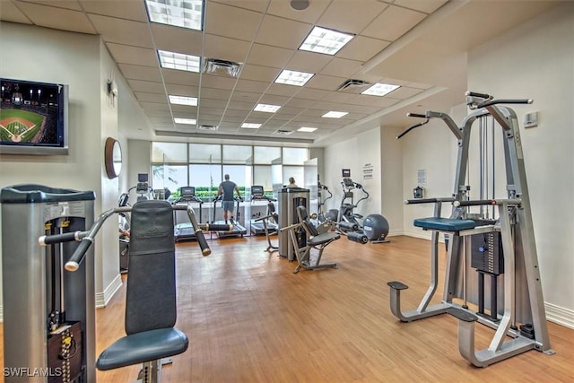 workout area featuring wood finished floors, baseboards, a drop ceiling, and visible vents