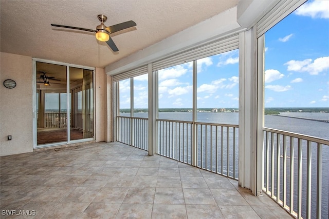 unfurnished sunroom featuring ceiling fan and a water view