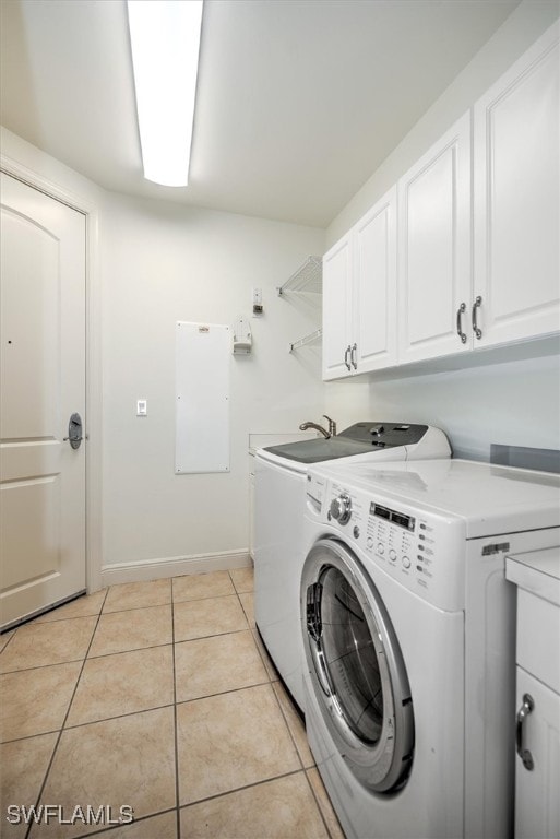 laundry area featuring washer and dryer, light tile patterned floors, and cabinets