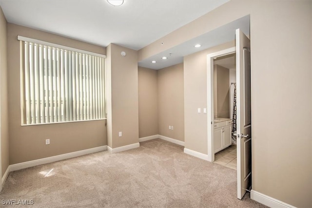 empty room featuring recessed lighting, light colored carpet, and baseboards