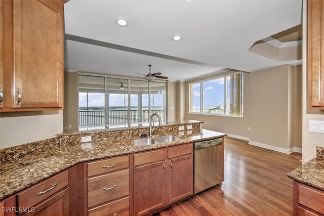 kitchen with a sink, stainless steel dishwasher, wood finished floors, and a healthy amount of sunlight