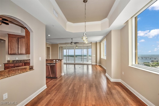 unfurnished dining area featuring ceiling fan, a raised ceiling, crown molding, and wood-type flooring