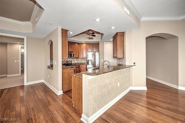 kitchen with arched walkways, dark wood-style flooring, brown cabinetry, and appliances with stainless steel finishes