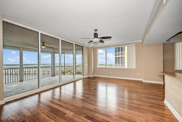 unfurnished living room with ornamental molding, ceiling fan, and baseboards