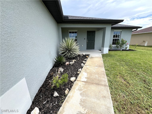 view of exterior entry with a lawn