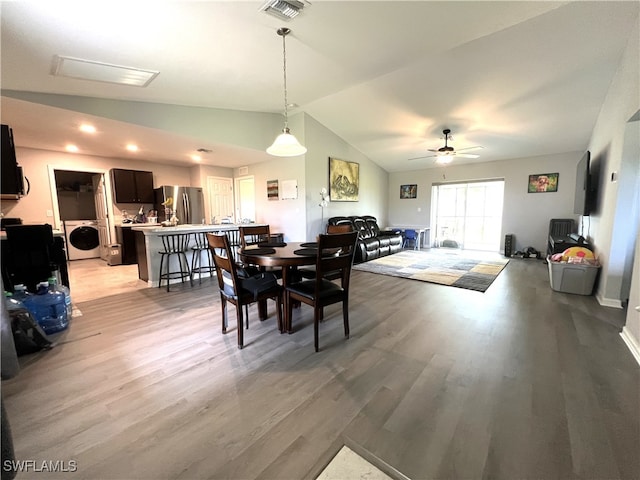 dining space featuring light wood-type flooring, vaulted ceiling, washer / clothes dryer, and ceiling fan