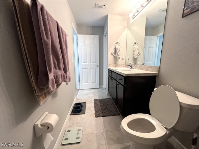 bathroom featuring tile patterned flooring, toilet, and vanity