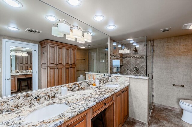 bathroom with tile patterned flooring, double vanity, tile walls, toilet, and a shower with door