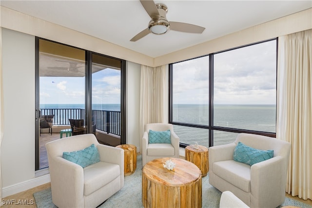 living area featuring ceiling fan and a water view