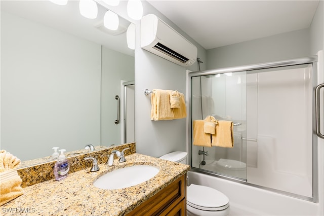 full bathroom with a wall mounted AC, vanity, bath / shower combo with glass door, and toilet