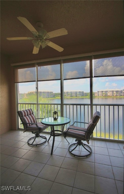 unfurnished sunroom featuring ceiling fan and a water view