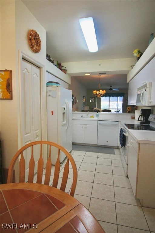 kitchen featuring pendant lighting, white appliances, light tile patterned floors, white cabinetry, and a chandelier