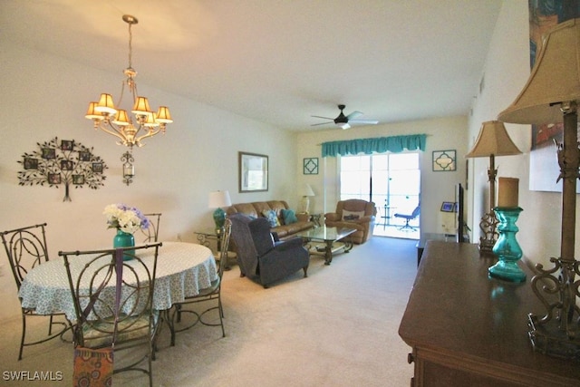 carpeted living room featuring ceiling fan with notable chandelier