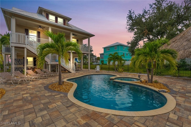 pool at dusk with a patio area, an in ground hot tub, and ceiling fan