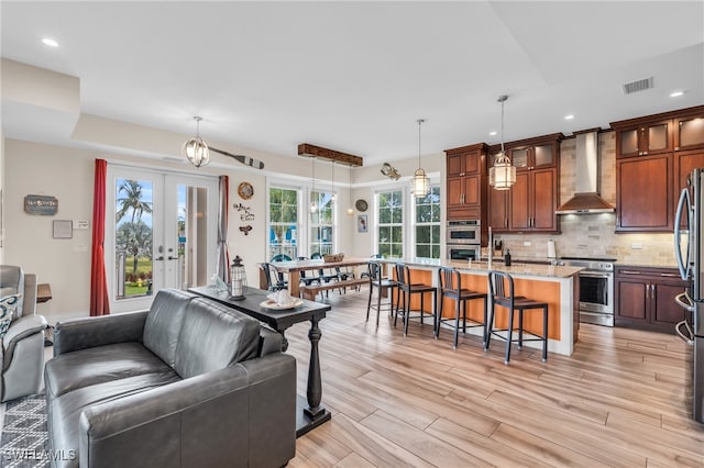 living room with light wood-type flooring, a wealth of natural light, and french doors