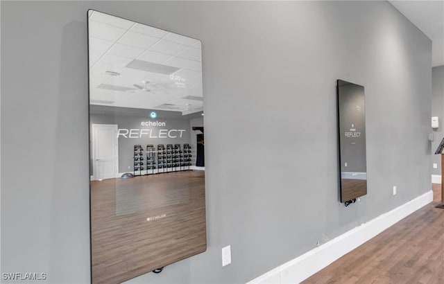 corridor with hardwood / wood-style floors and a drop ceiling