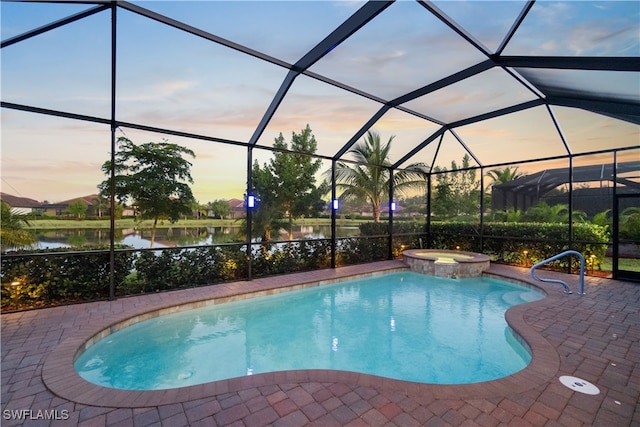 pool at dusk with a lanai, an in ground hot tub, and a patio area