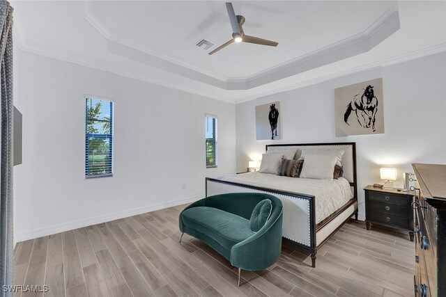 bedroom featuring ceiling fan, multiple windows, and a tray ceiling