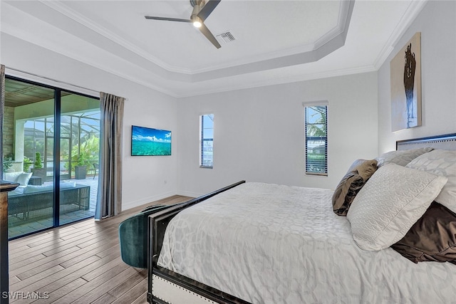 bedroom with crown molding, a tray ceiling, ceiling fan, access to exterior, and hardwood / wood-style floors