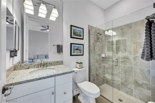 bathroom with ceiling fan, an enclosed shower, vanity, and toilet