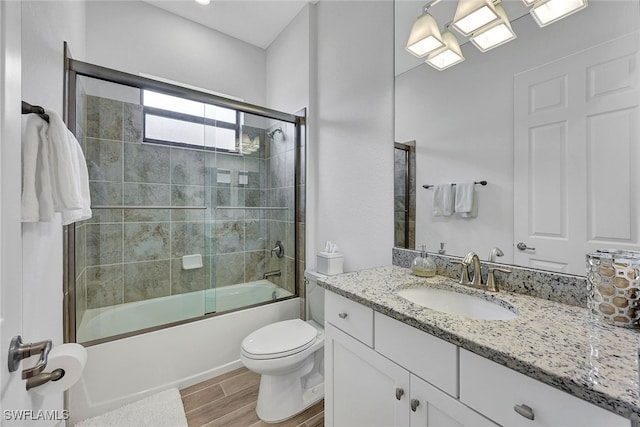 full bathroom featuring toilet, combined bath / shower with glass door, and vanity