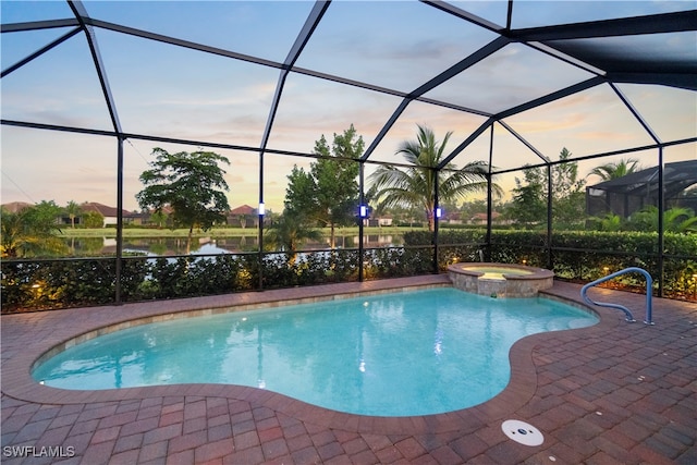 pool at dusk with glass enclosure, an in ground hot tub, and a patio