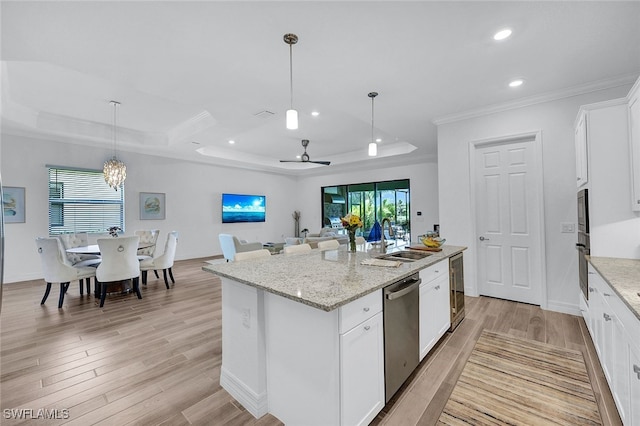 kitchen featuring pendant lighting, a raised ceiling, white cabinets, a kitchen island with sink, and stainless steel appliances