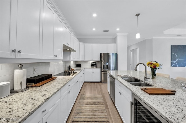 kitchen featuring sink, light wood-type flooring, tasteful backsplash, white cabinetry, and stainless steel appliances