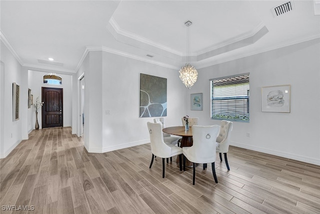 dining room with a raised ceiling, crown molding, and hardwood / wood-style floors