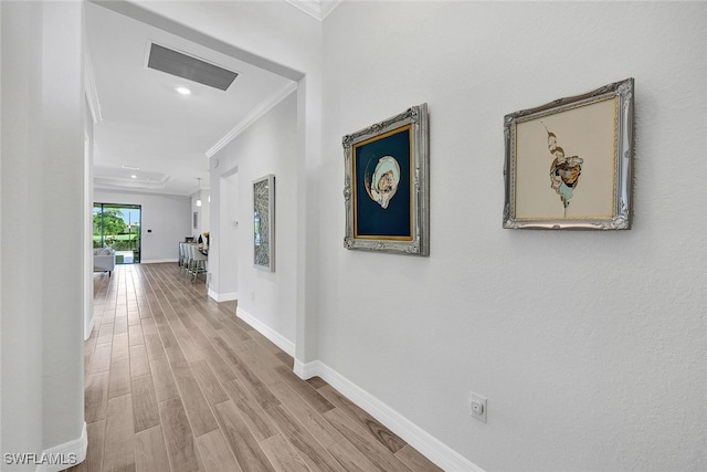 hall with ornamental molding and light hardwood / wood-style floors