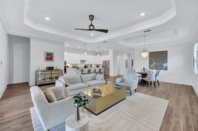 living room featuring ceiling fan, a raised ceiling, light hardwood / wood-style flooring, and crown molding