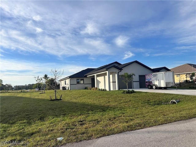 view of side of property with an attached garage, concrete driveway, a lawn, and stucco siding