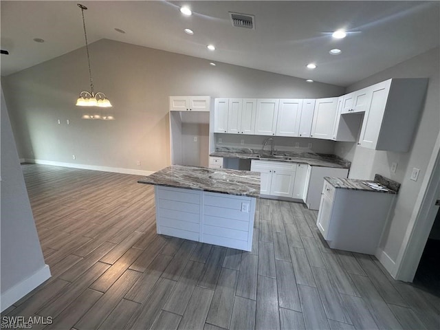 kitchen with a kitchen island, a notable chandelier, hardwood / wood-style floors, and white cabinets